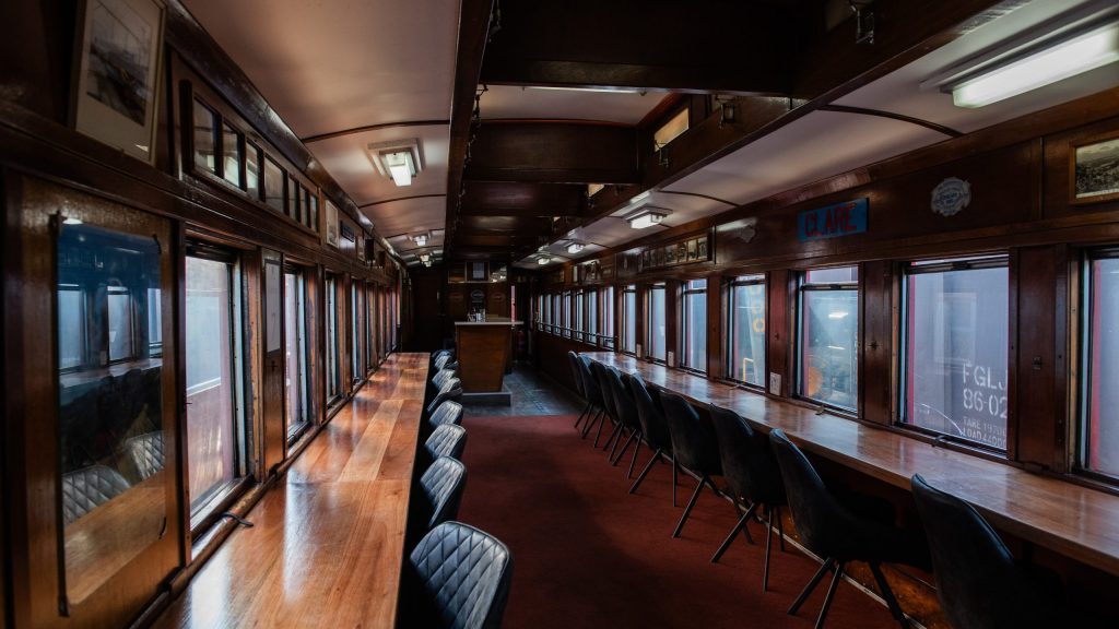 Interior of an empty vintage train car with wooden tables and chairs.