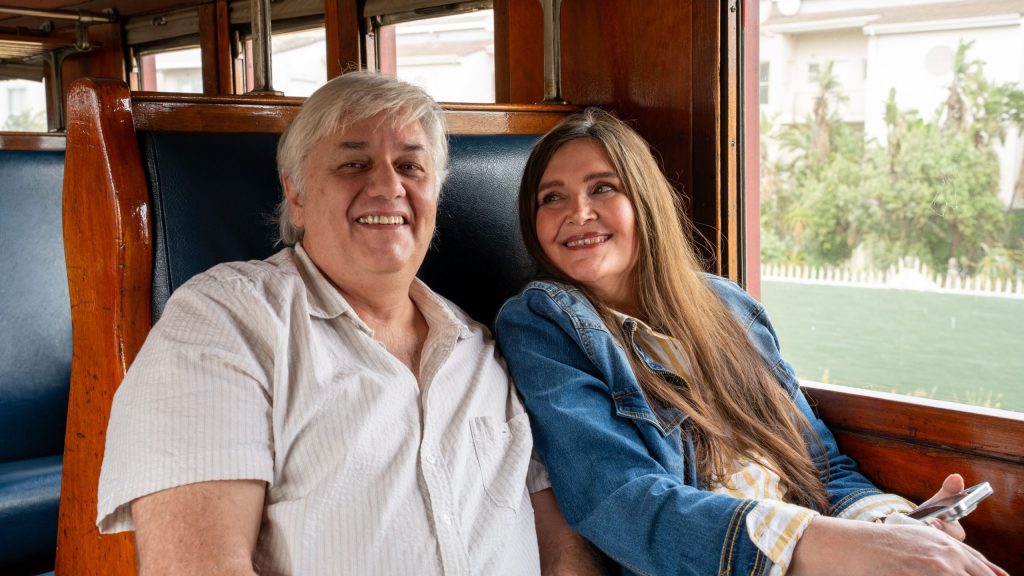 Man and woman smiling, sitting in a vintage train car.