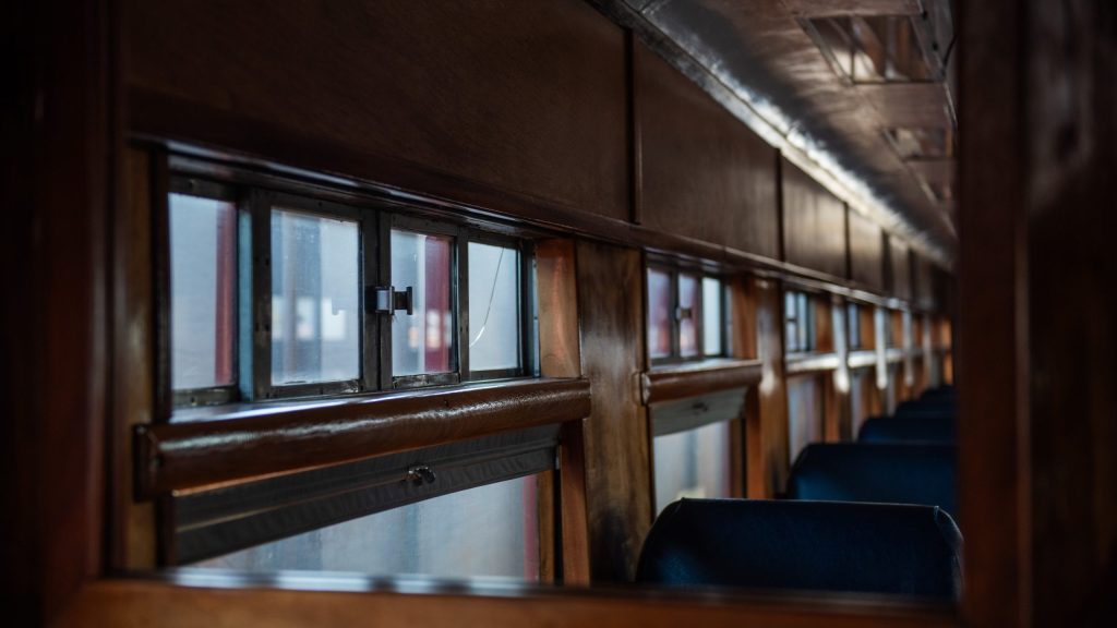 Interior of vintage train car with wooden trim and rows of seats.