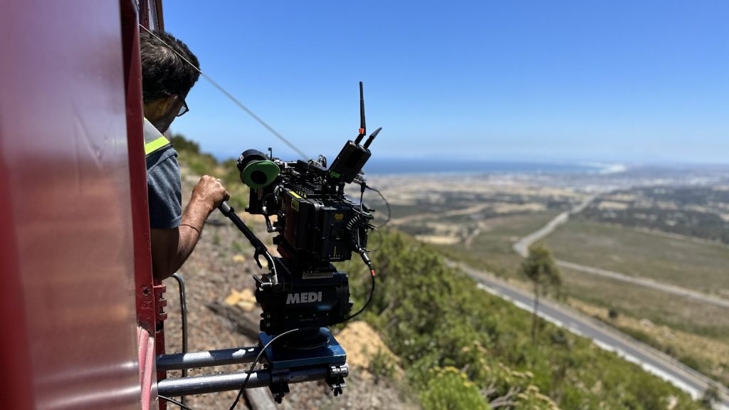Person filming landscape from a train using a camera setup.