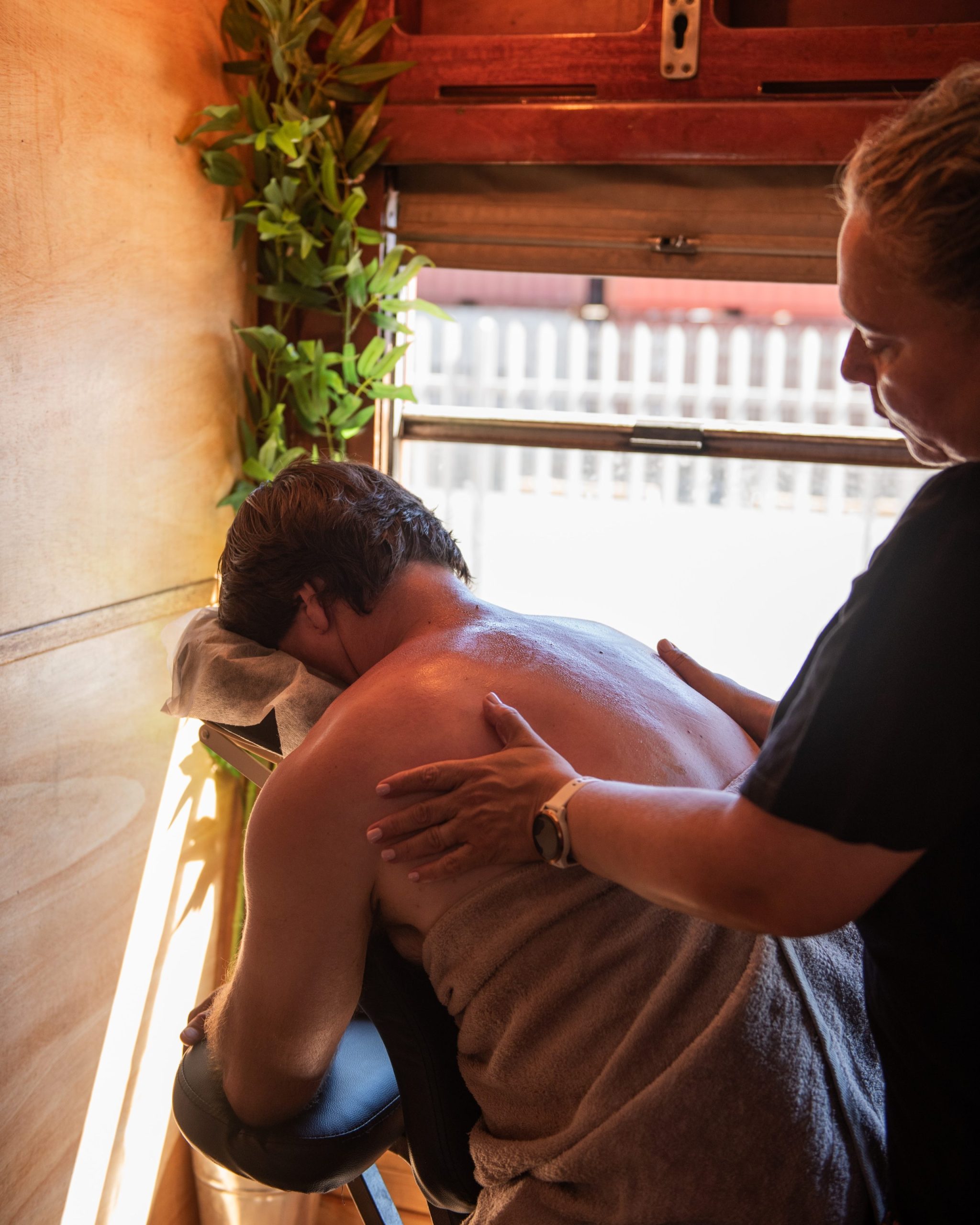 Person receiving a back massage in a chair near a window.