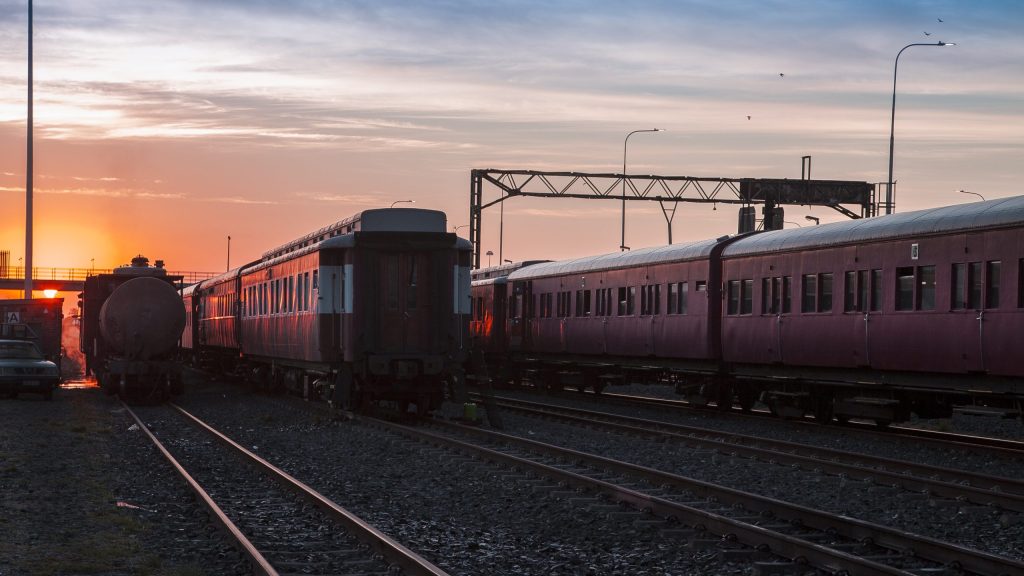 Sunset over train yard with red trains and metal structures