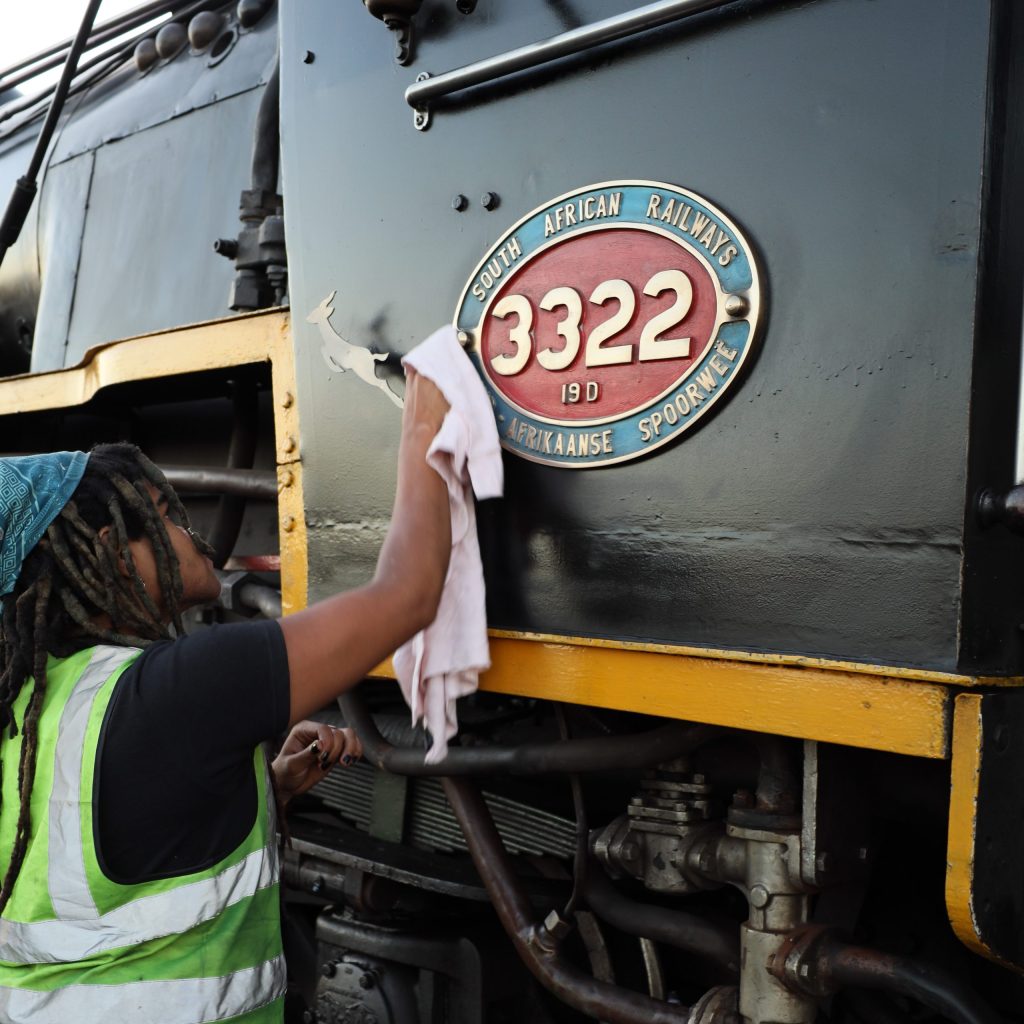 Person polishing a vintage train engine labeled '3322' with a cloth.